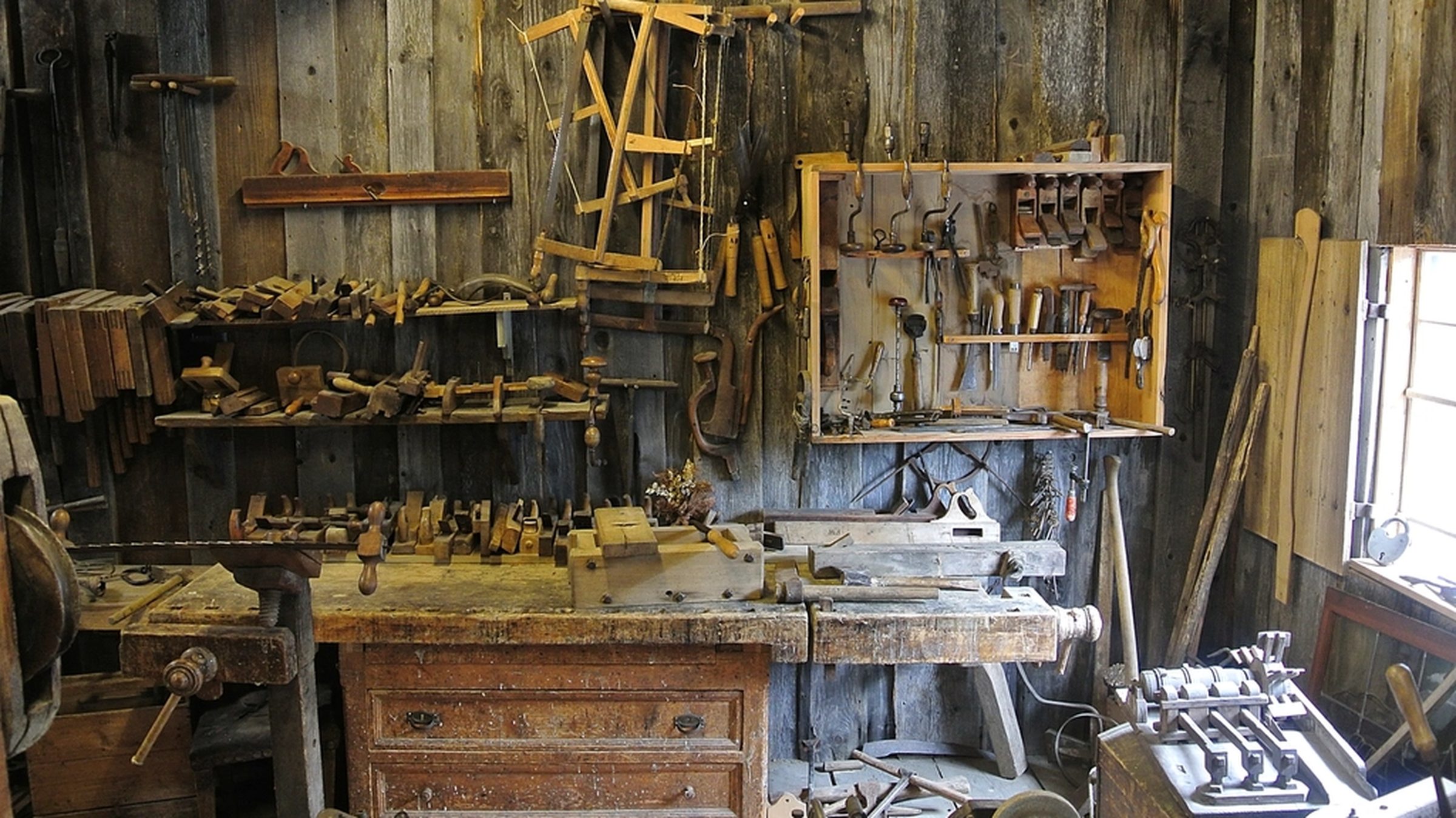 A traditional woodworking workshop, tools racked above a workbench